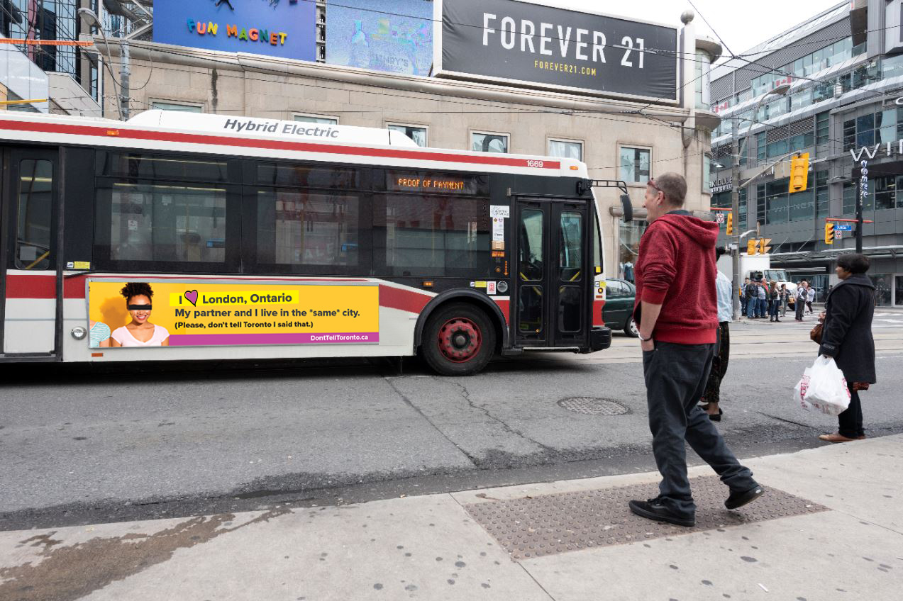 An image of a Toronto Transit bus driving past with a Don't Tell Toronto advertisement on the side of it.